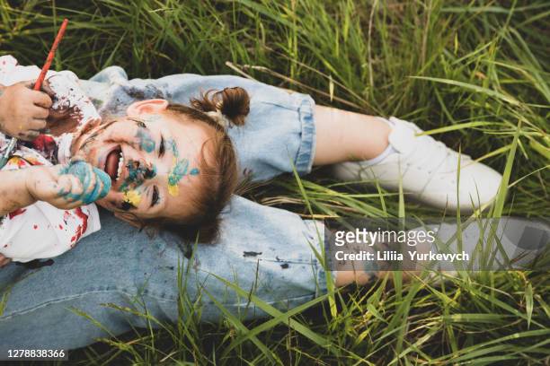 mom and her little daughter have fun and paint each other with colored paints. - baby paint stock pictures, royalty-free photos & images