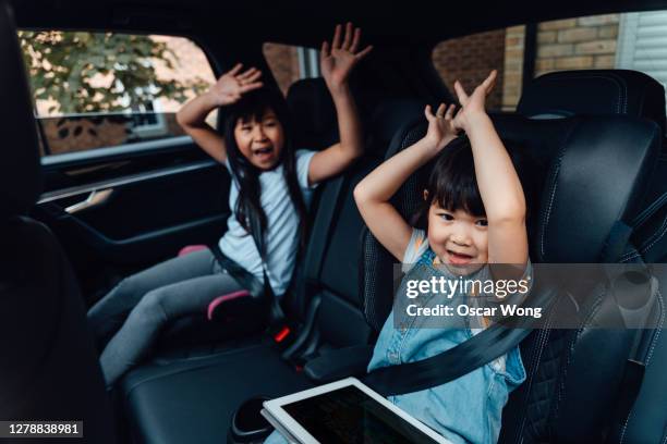 excited young sisters waving hands in the car - family with two children stockfoto's en -beelden