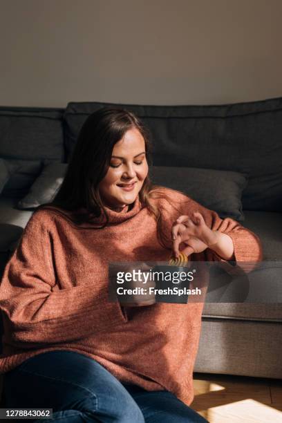 mulher bonita em um suéter quente desfrutando de uma xícara de café em casa em uma manhã de inverno - dipping - fotografias e filmes do acervo