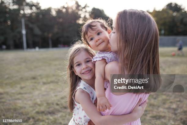three smiling beautiful sisters hugging - sibling stock pictures, royalty-free photos & images