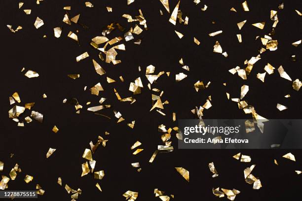 golden confetti falling against black background - confetti gold ストックフォトと画像