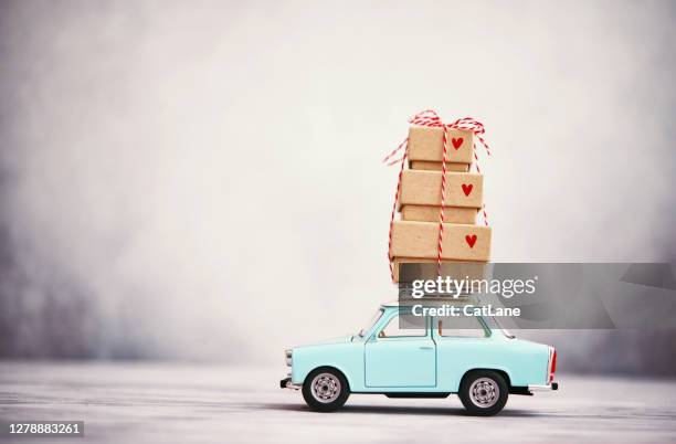 little blue car with gift stack on roof rack - small gift box stock pictures, royalty-free photos & images