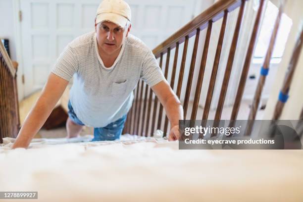 mature adult male straightening drop cloth on stairway - staircase house stock pictures, royalty-free photos & images