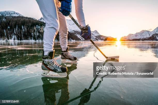 man with skates playing ice hockey on lake sils, switzerland - wintersport stock-fotos und bilder