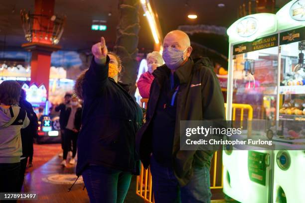 People wearing face masks play games in an amusement arcade on October 06, 2020 in Blackpool, England. This year to help boost the tourism trade,...