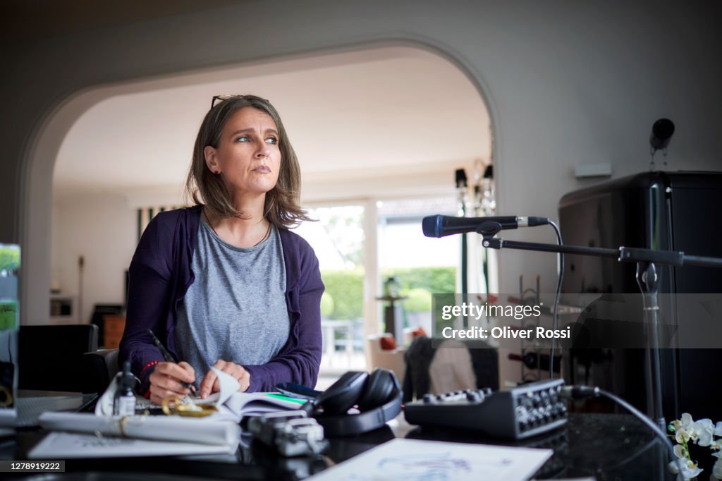 Mature woman in studio at home with sound recording equipment