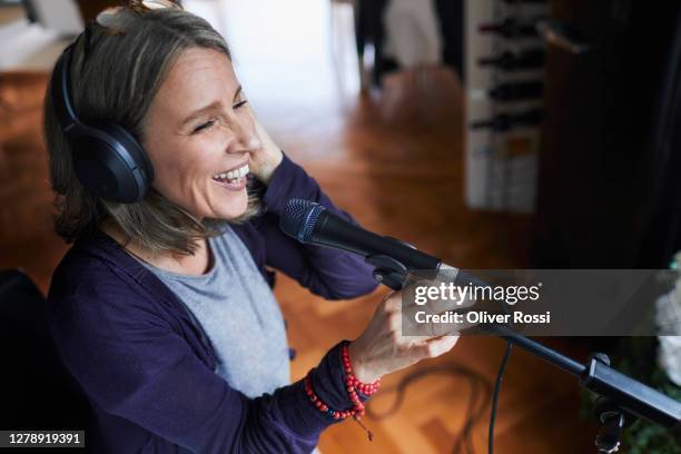 laughing mature woman with headphones and microphone - radio host stock pictures, royalty-free photos & images