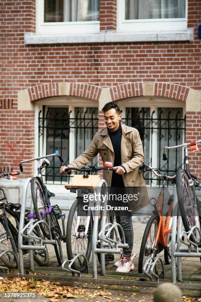 millennial aziatische forens in de stad met fiets - amsterdam bike stockfoto's en -beelden
