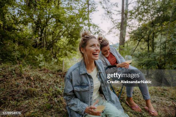 jonge vrouwen die door kampvuur zitten - haardvuur stockfoto's en -beelden