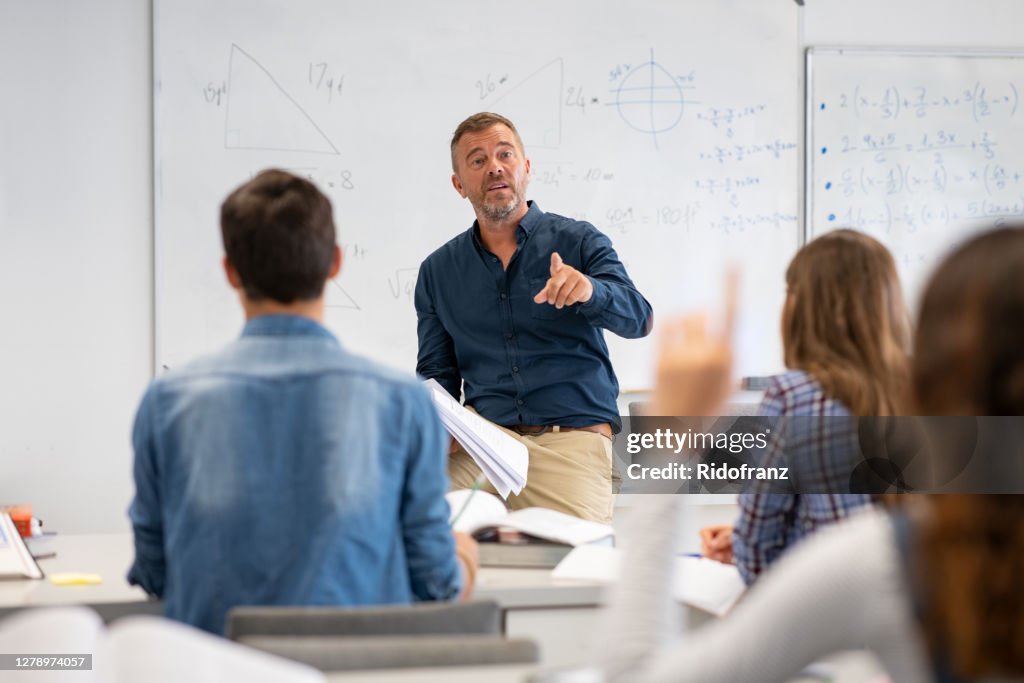 Student raising hand in classroom at the high school