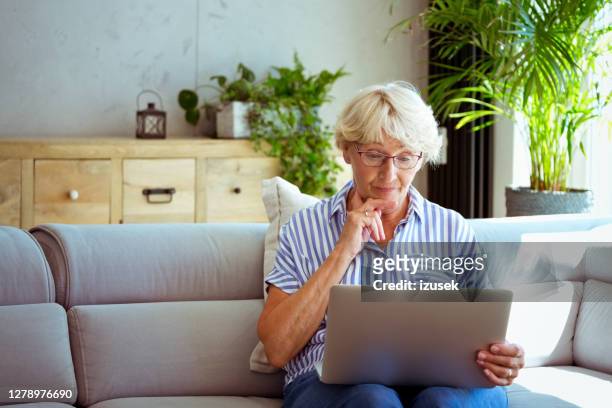 senior woman using laptop at home - senior using laptop stock pictures, royalty-free photos & images