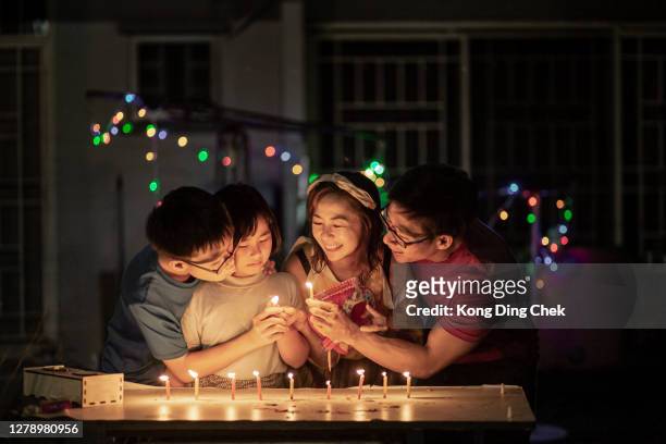 festa della torta lunare per la festa della torta di luna della famiglia cinese in asia. accesero la candela nel parco pubblico con la faccia sorridente. - parents children blow candles asians foto e immagini stock