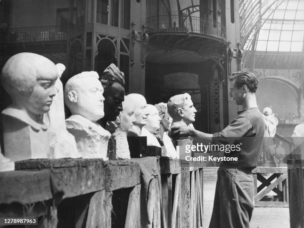 Porter arranging carved busts in a row as the exhibits are installed ahead of the annual exhibition of French artists at the Grand Palais in Paris,...