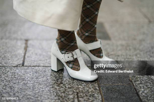 Guest wears brown checked tights, white shoes, outside Miu Miu, during Paris Fashion Week - Womenswear Spring Summer 2021, on October 06, 2020 in...