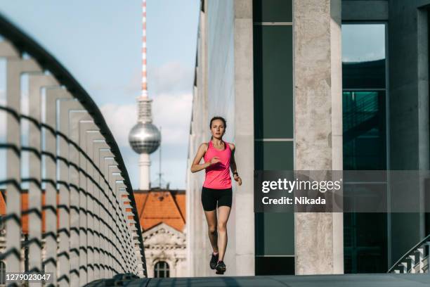 frau läuft in einem modernen geschäftsviertel in berlin, deutschland - joggerin stock-fotos und bilder