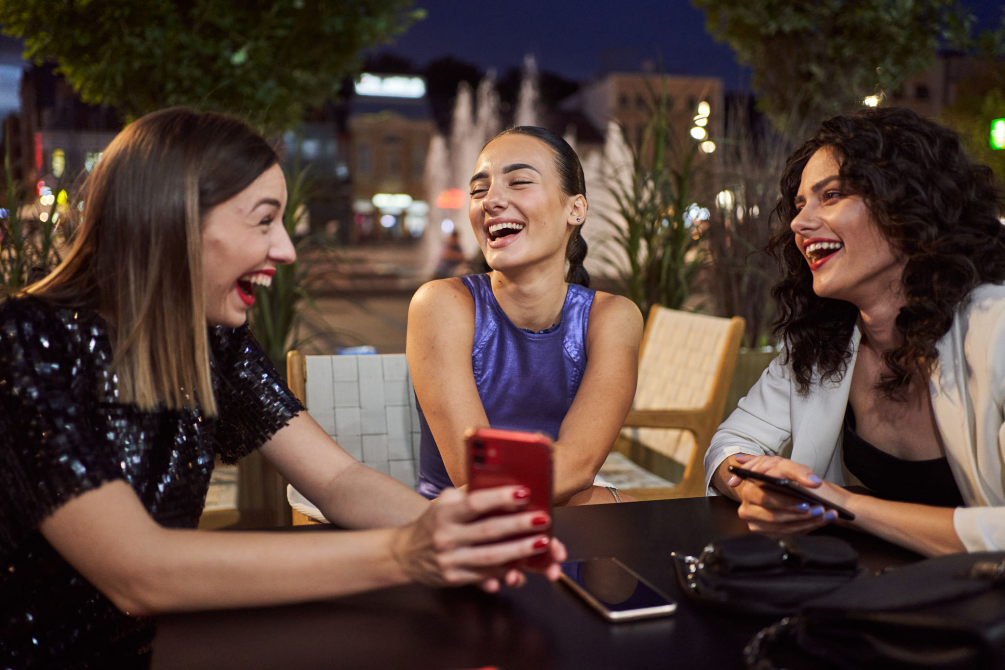 Ecstatic women laughing while looking at a mobile phone at a cafe Ecstatic women laughing while looking at a mobile phone at a cafe
