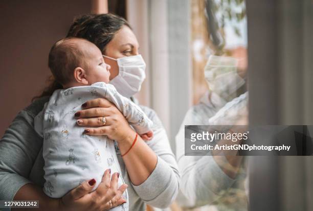 mother with protective mask and her newborn baby. - pandemic lockdown stock pictures, royalty-free photos & images