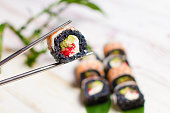 Sushi Roll with avocado, cream cheese. bamboo leaves and plant on background.