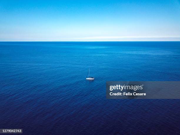 aerial view of a solo sailing boat in the middle of the sea - albero maestro foto e immagini stock