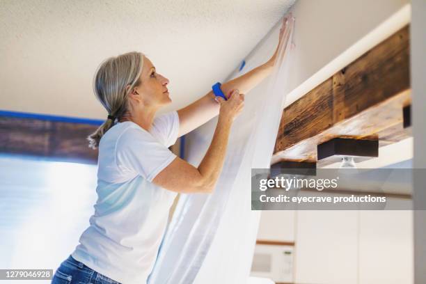 mujer adulta usando cinta de pintor y plástico para la preparación de la pintura - molde fotografías e imágenes de stock