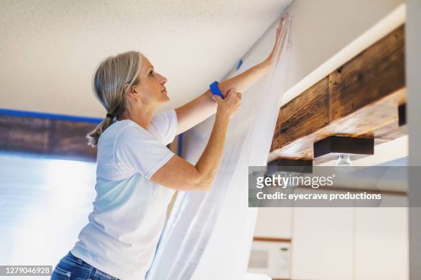 adult female using painter's tape and plastic for painting preparation - paint preparation stock pictures, royalty-free photos & images
