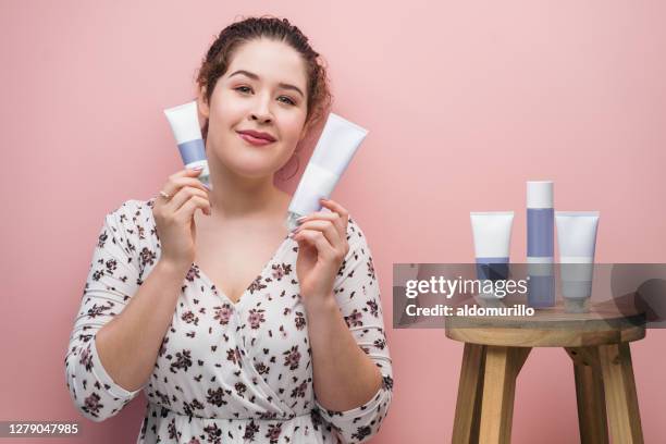 jonge latijnse vrouw die schoonheidsproducten houdt en camera bekijkt - latin beauty stockfoto's en -beelden