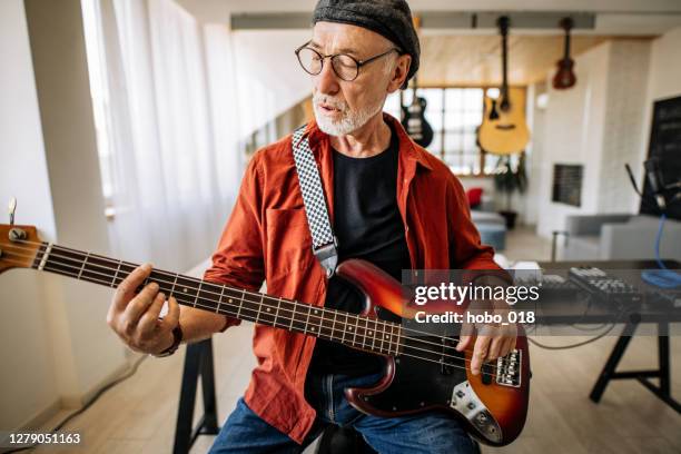 ritratto di musicista senior con chitarra elettrica seduto nel suo studio di registrazione musicale - chitarra elettrica foto e immagini stock