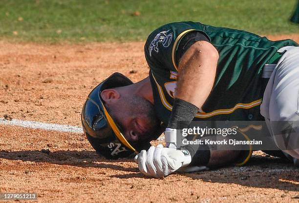 Tommy La Stella of the Oakland Athletics reacts after being hit by a pitch by Brooks Raley of the Houston Astros during the eighth inning in Game...