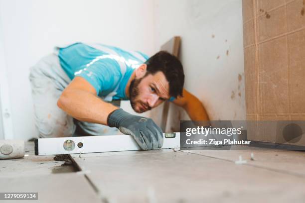 handyman using a level to see if the tiles are leveled - leveled stock pictures, royalty-free photos & images