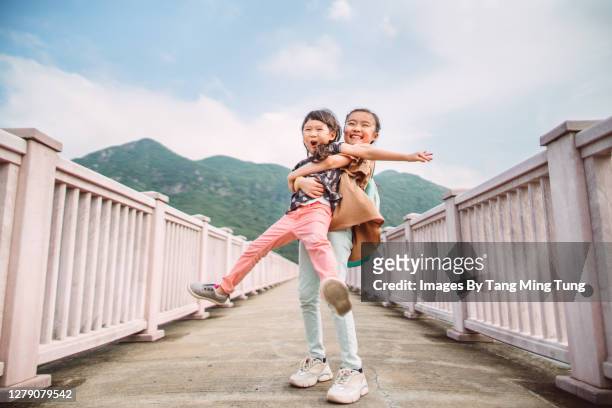 little sibling playing joyfully on bridge in sunny day - human limb stock pictures, royalty-free photos & images