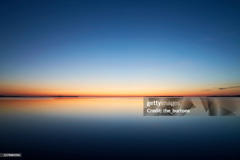 Sunset by the sea, the sky is reflected in the smooth sea
