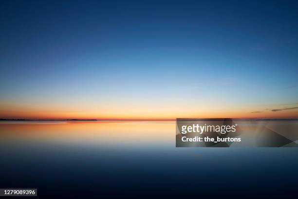 sunset by the sea, the sky is reflected in the smooth sea - imbrunire foto e immagini stock