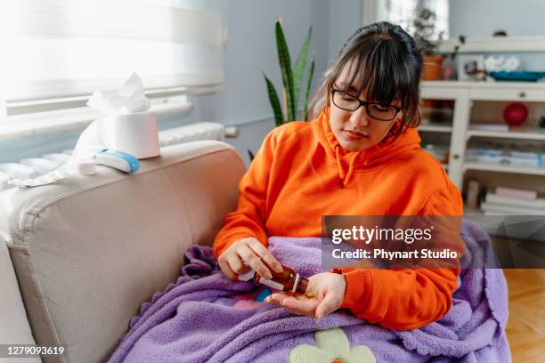 sickness, seasonal virus problem concept. woman being sick having flu lying on sofa looking at temperature on thermometer. sick woman lying in bed with high fever. cold flu and migraine - anemia stock pictures, royalty-free photos & images