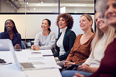 Line Of Businesswomen In Modern Office Listening To Presentation By Colleague