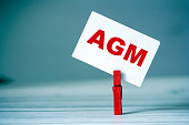 Reminder sticky note with clothes pin on table. Sticky note with word AGM. Business strategy