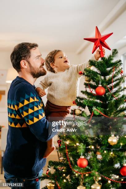father and son decorating christmas tree - decorating the christmas tree stock pictures, royalty-free photos & images