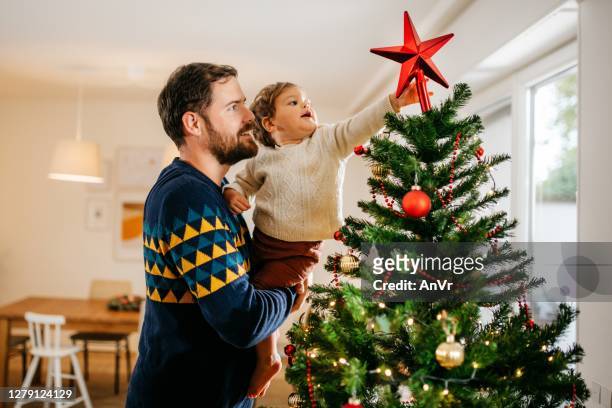 father and son decorating christmas tree - christmas tree decorations imagens e fotografias de stock