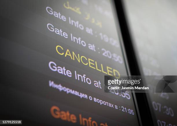 flight cancelled illuminated on airport arrivals board - cancelación fotografías e imágenes de stock