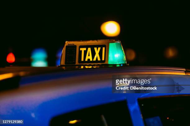 luminous of a lit taxi in madrid, spain at night - taxi españa stockfoto's en -beelden