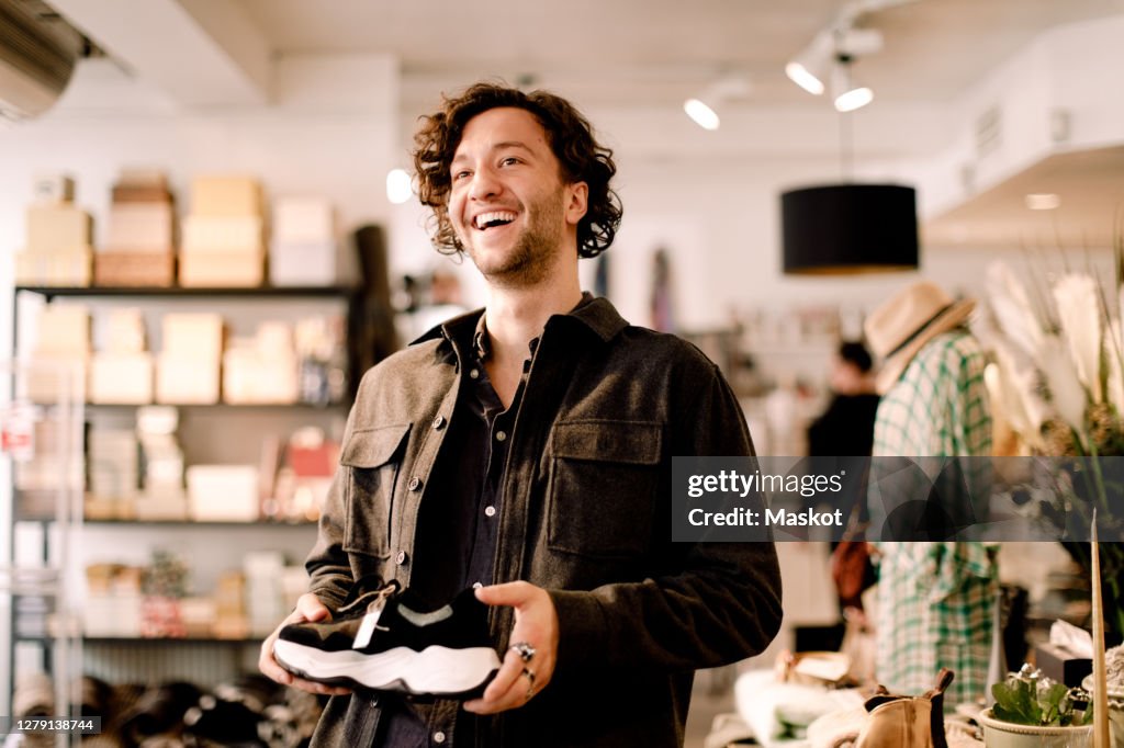 Happy male customer looking away while buying shoe at retail store