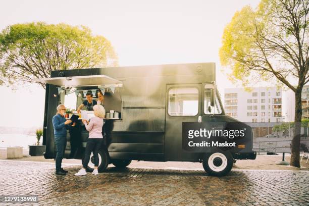 owners talking to senior customers while standing in commercial land vehicle - foodtruck stockfoto's en -beelden