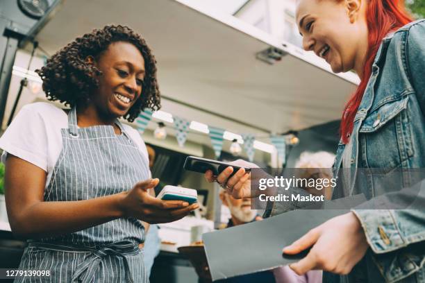 low angle view of customer paying through smart phone in city - food truck payments stock pictures, royalty-free photos & images