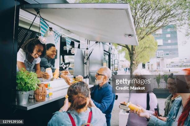 smiling male and female customers talking to food truck owners in city - foodtruck stockfoto's en -beelden