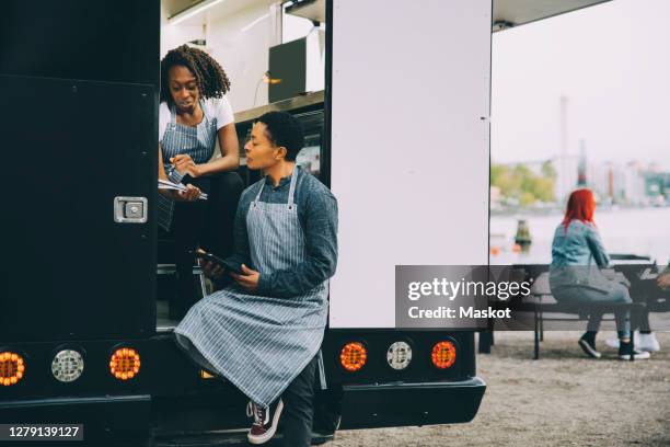 female owner and assistant discussing in food truck - man lady phone ipad outside stock pictures, royalty-free photos & images