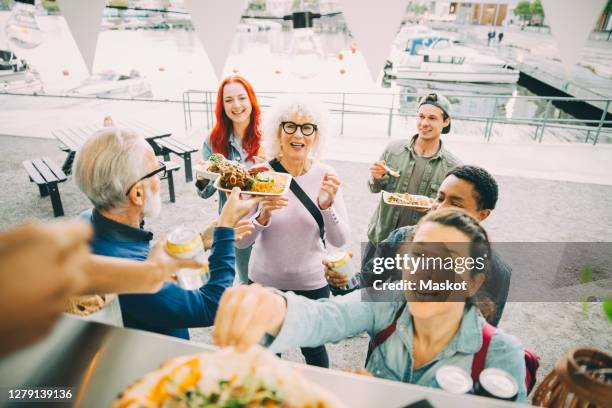 Smiling male and female customers enjoying at food truck in city