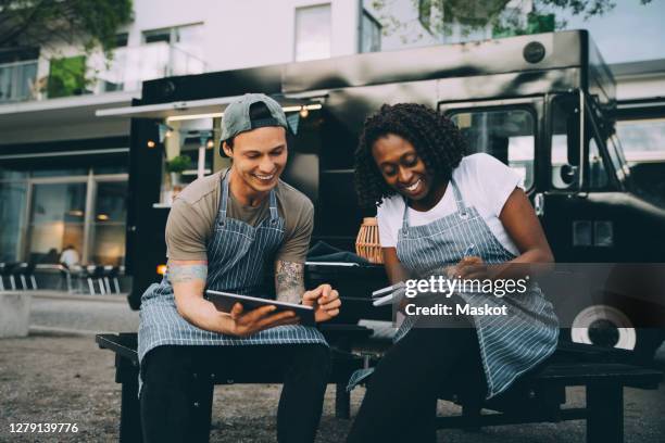 smiling male and female owners working against food truck in city - woman smiling facing down stock pictures, royalty-free photos & images