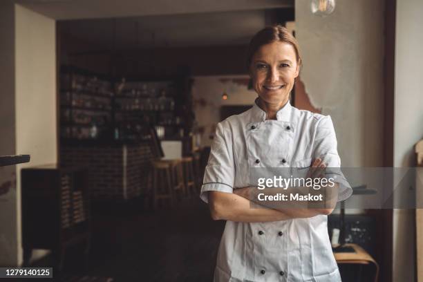 portrait of smiling chef with arms crossed in restaurant - köchin stock-fotos und bilder