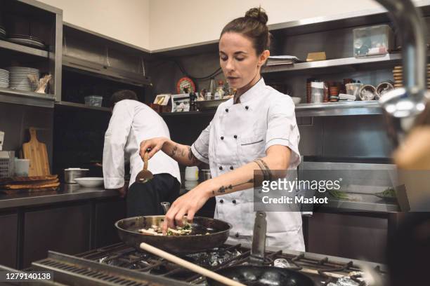female chef preparing food at restaurant - chef male kitchen stock pictures, royalty-free photos & images
