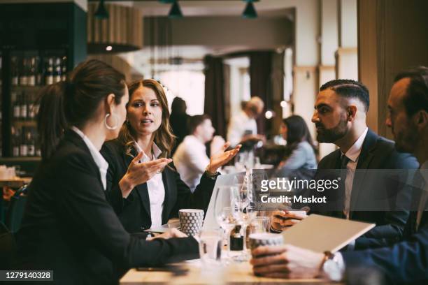 female entrepreneur discussing with colleagues in restaurant - corporate lunch stock pictures, royalty-free photos & images