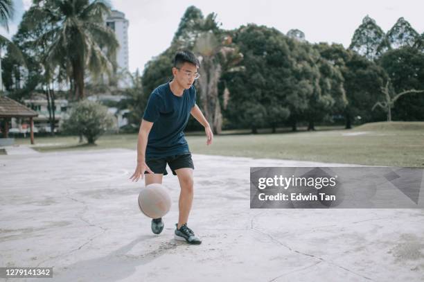 アジアの中国の十代の少年は、週末の朝にバスケットボールコートで得点し、練習する準備をしています - トレーニングドリル ストックフォトと画像